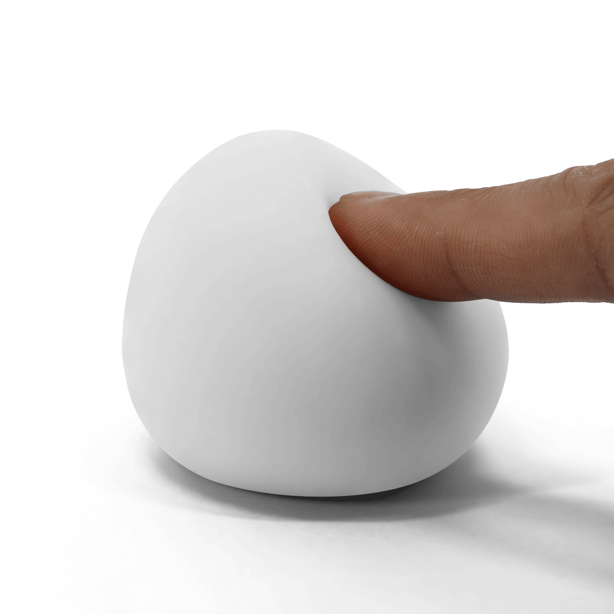 A finger presses into a soft, white, egg-shaped TPR male masturbator on a white background.