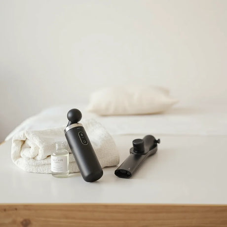 Discreet male personal massager on a bedside table with lubricant and a towel