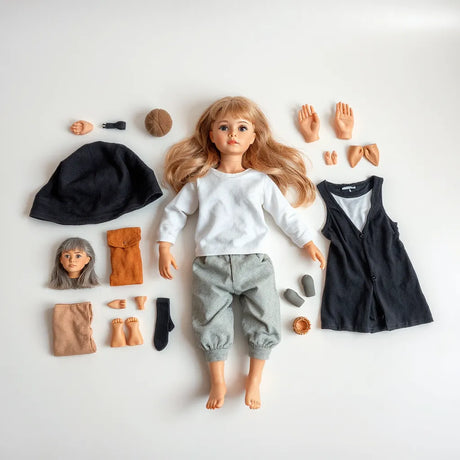 Customizable adult doll with interchangeable head, hair, and outfit components on a clean table