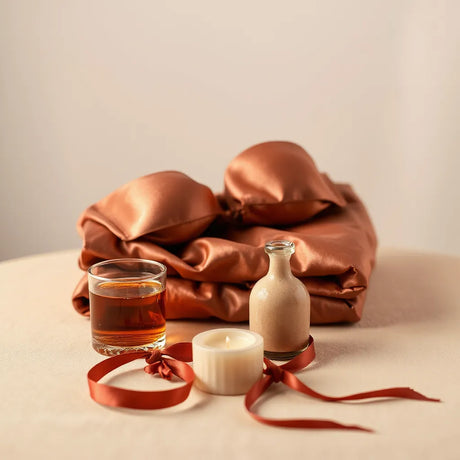 Elegant tabletop with satin lingerie, candle, and massage oil accessories for a luxurious gift moment