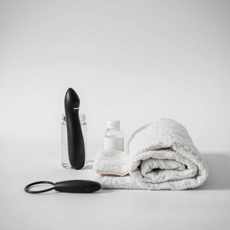 Ergonomic adult toy for men on a neutral surface with lubricant and a folded towel