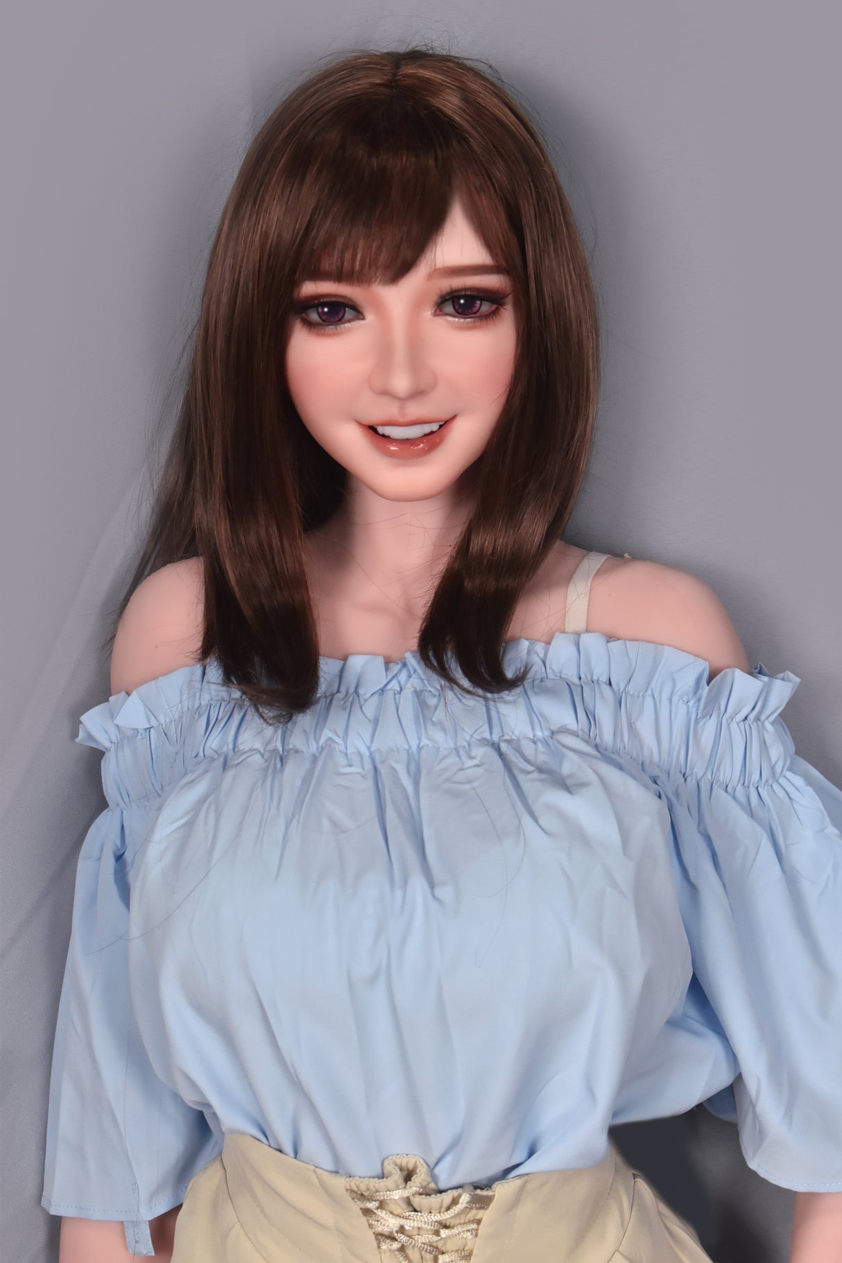 sex doll wearing a light blue off-shoulder top against a gray background